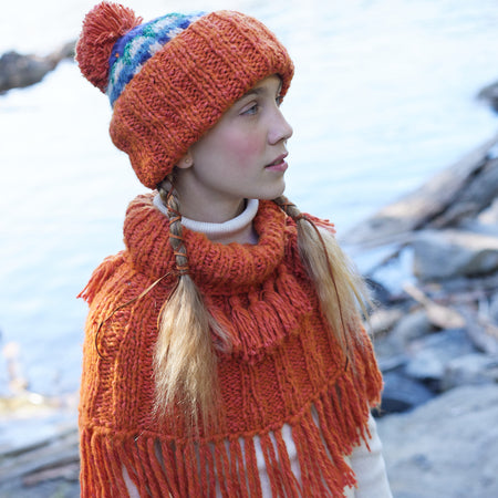 girl wearing orange hand knit wool slip over shrug with tassels