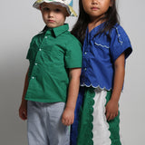 Two children wearing colorful outfits against a plain background