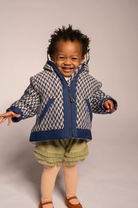 baby girl wearing padded winter coat in blue and white herringbone wool fabric with hood