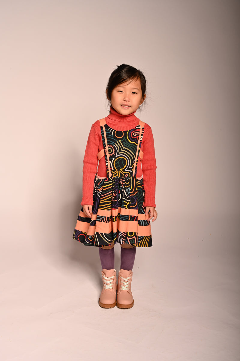 girl wearing cotton apron dress in all over print with pink stripes