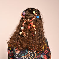 girl wearing set of 4 multicolored hair tie elastics with wooden beads on the end