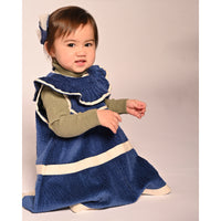 baby girl wearing corduroy blue dress with white ribbon stripes going across