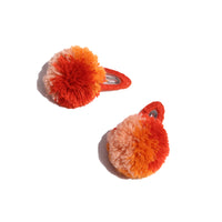 two barrette hair clips with a orange and red pom pom