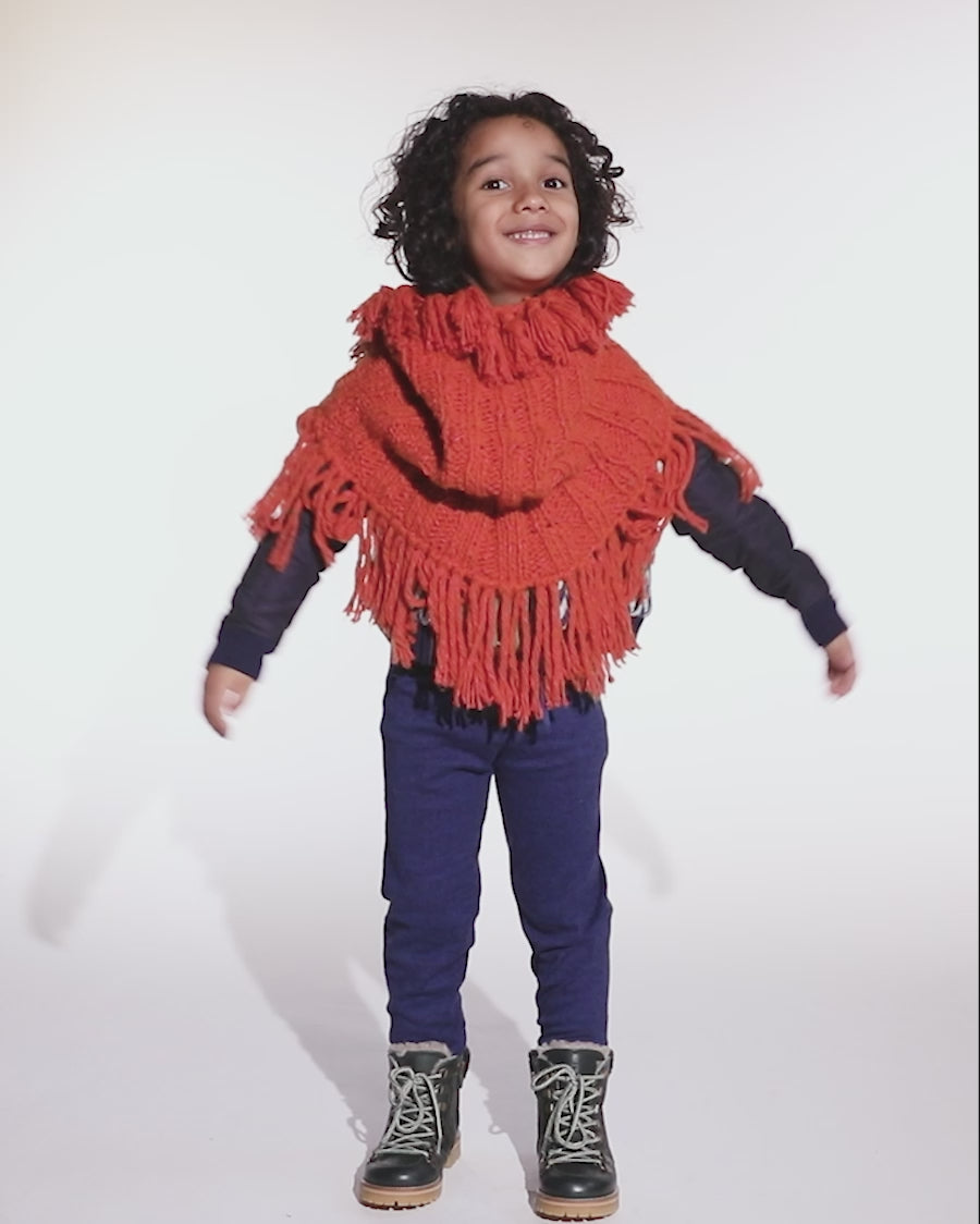 video of boy wearing orange hand knit wool slip over shrug with tassels